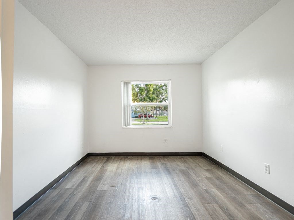 an empty room with a window and wood floors