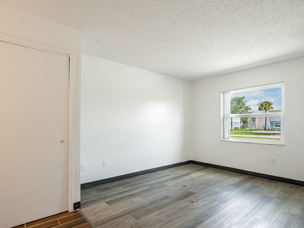 the spacious living room with wood flooring and a window