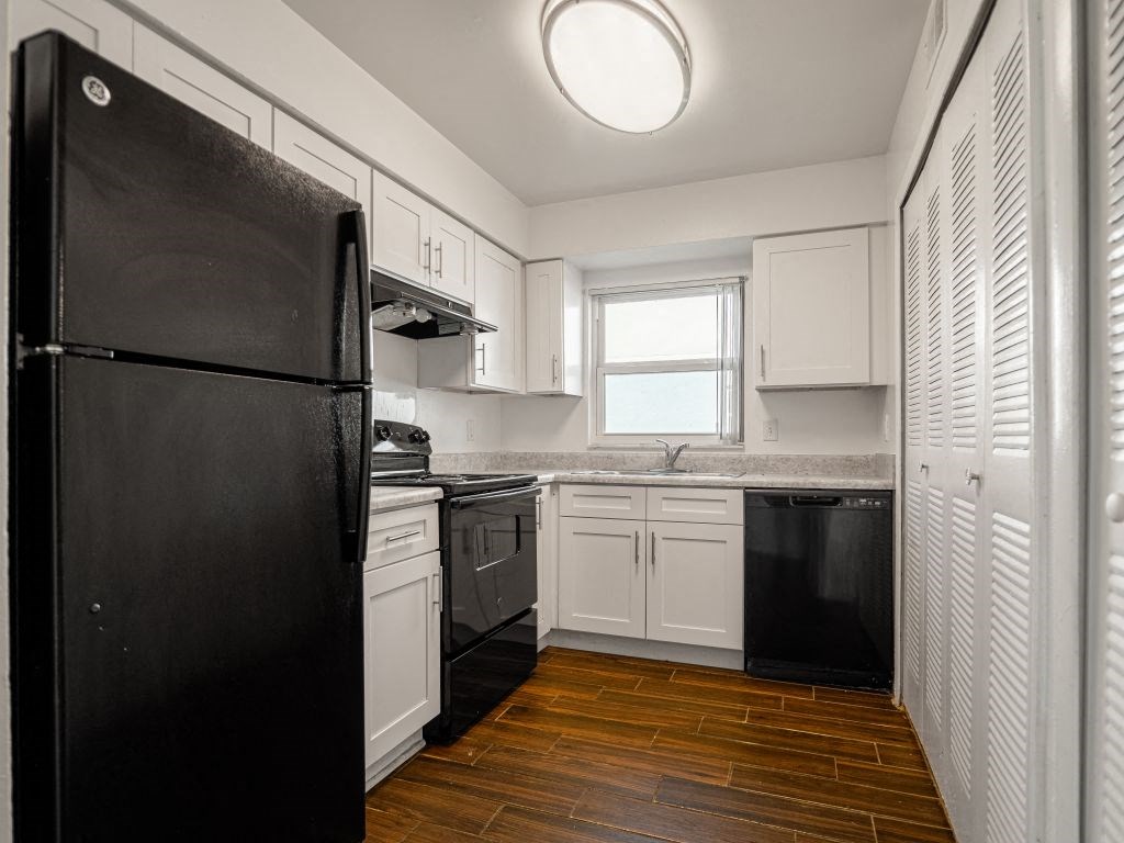 a kitchen with a black refrigerator and white cabinets