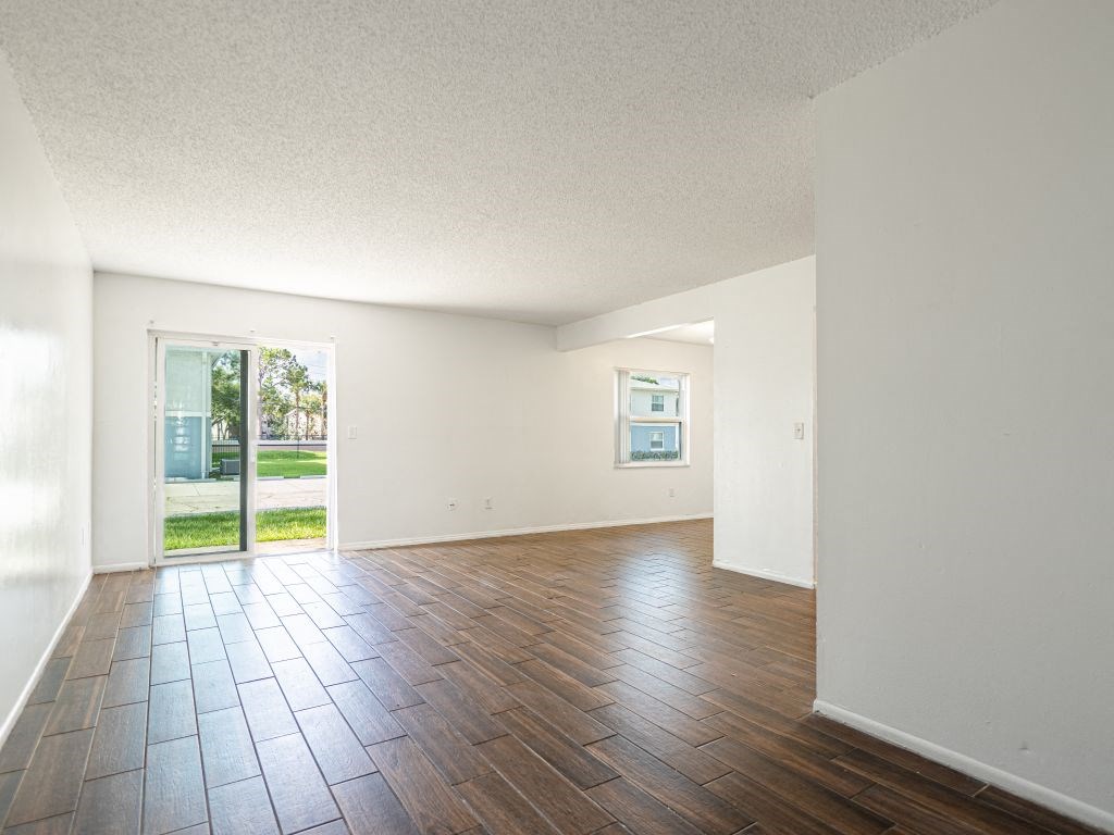 an empty living room with hard wood floors and a glass door