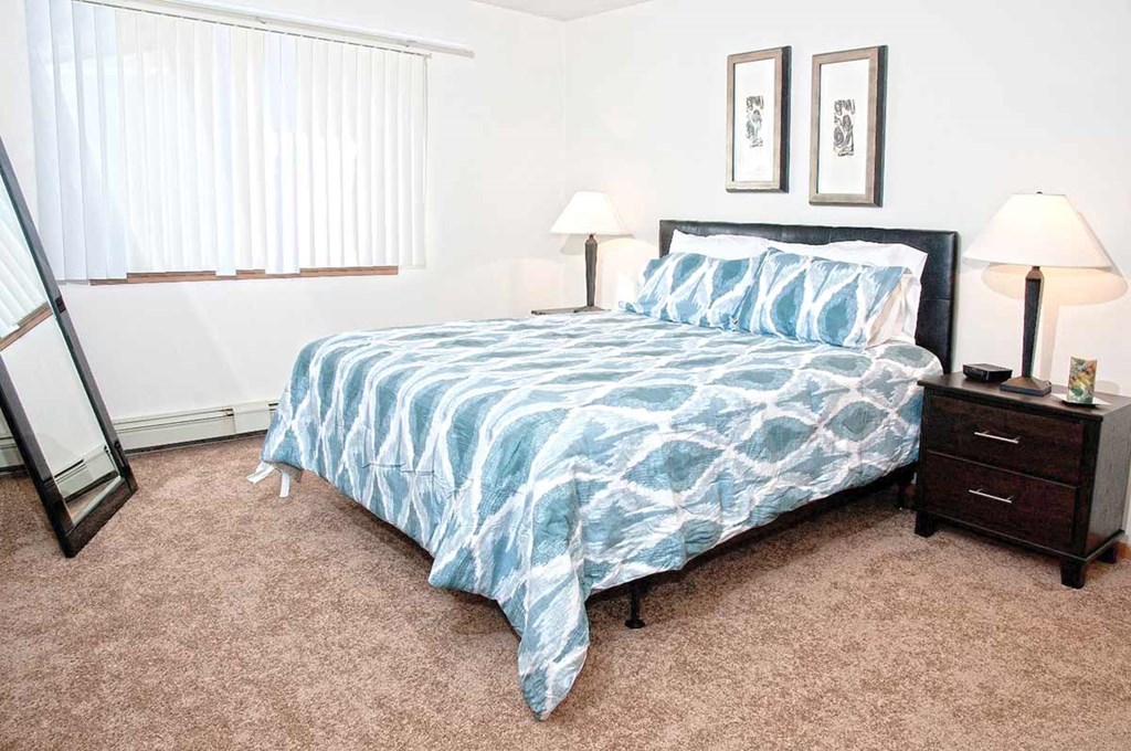 a bedroom with a bed and a window with blinds