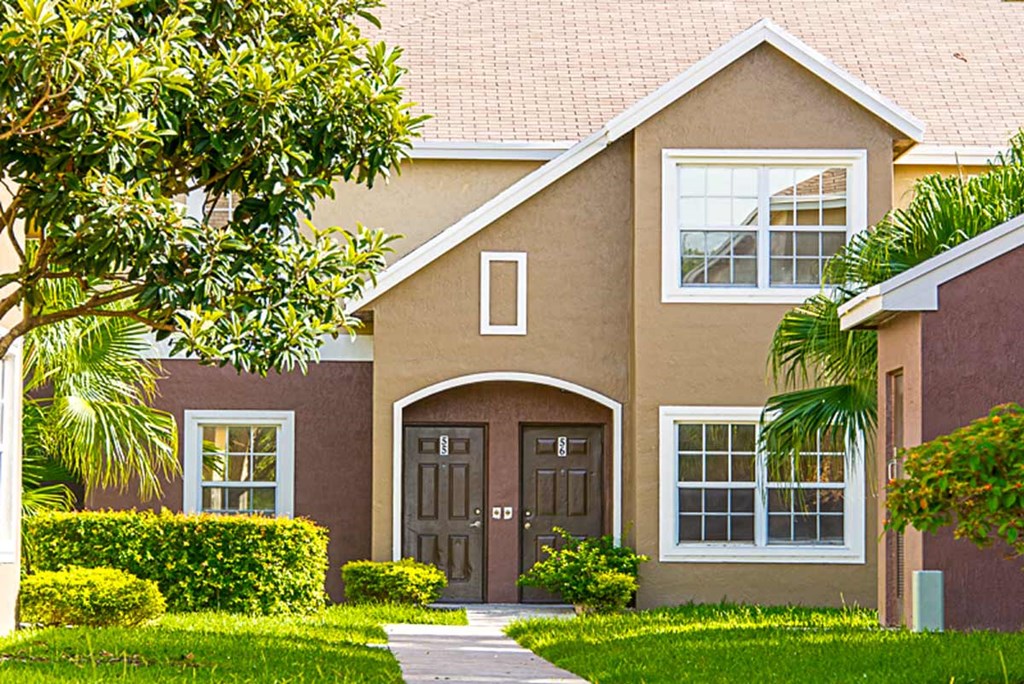 a brown house with a sidewalk in front of it