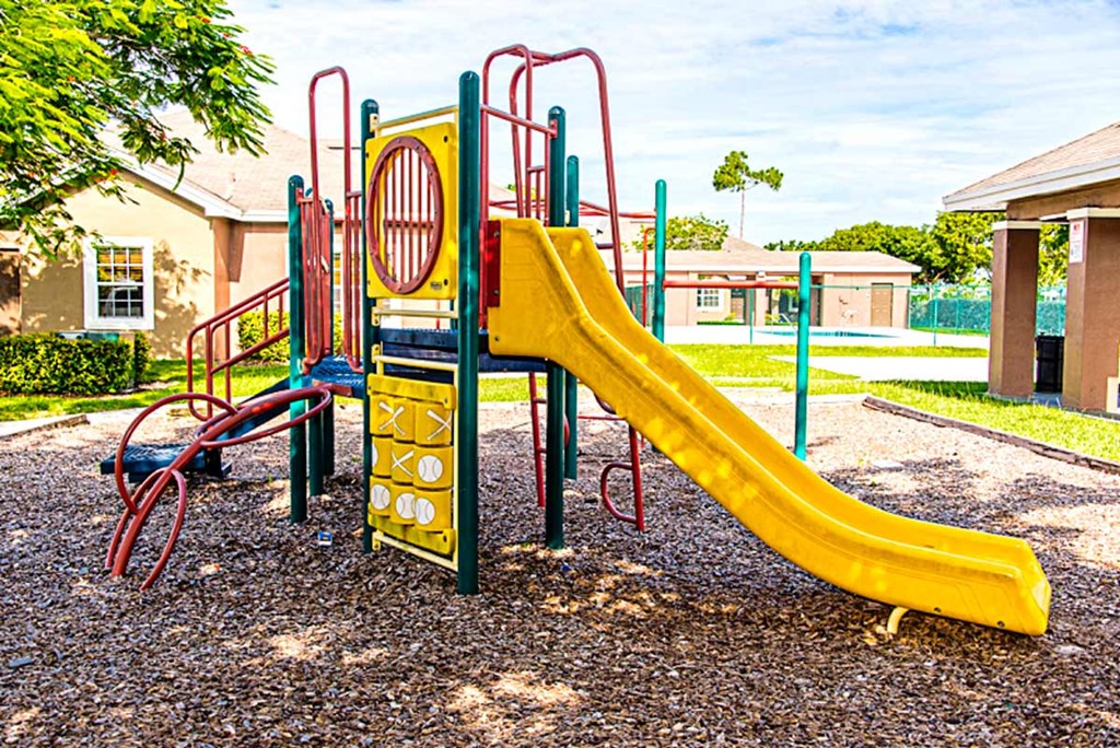 a playground with a yellow slide in a park