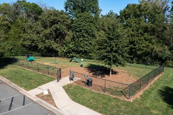 a park with a fenced in dog park and trees  at Abberly Green Apartment Homes by HHHunt, North Carolina,  28117