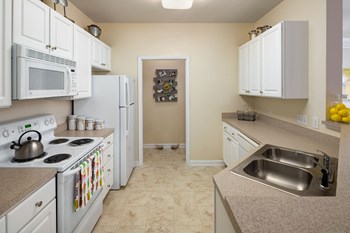 Kitchen With White Cabinetry And Appliances Kitchen With White Cabinetry And Appliances at Abberly Place at White Oak Crossing Apartments, HHHunt Corporation, North Carolina - Photo Gallery 2