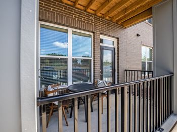a balcony with a table and chairs and a large window