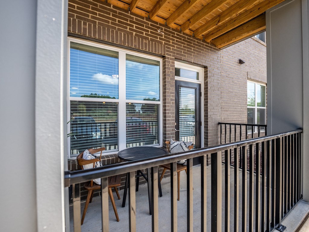 a balcony with a table and chairs and a large window