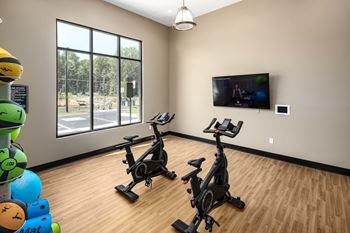 an exercise room with two treadmills and a flat screen tv