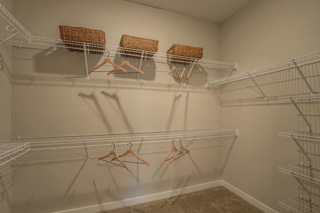 a spacious walk in closet with silver wire shelves and wicker baskets