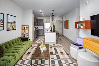 a living room with a green couch and a kitchen in the background
