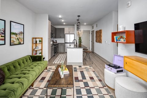a living room with a green couch and a kitchen in the backgroundat Abberly Foundry Apartment Homes, Nashville, TN, 37206