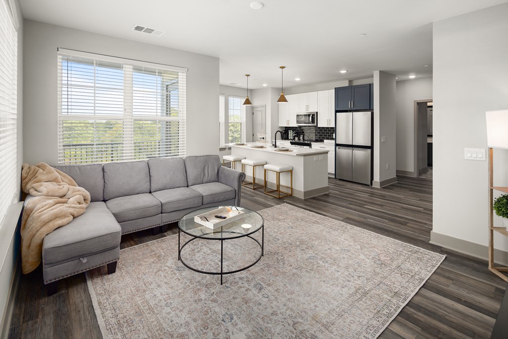 a living room with a couch a table and a kitchen in the background at Abberly Foundry Apartment Homes, Tennessee