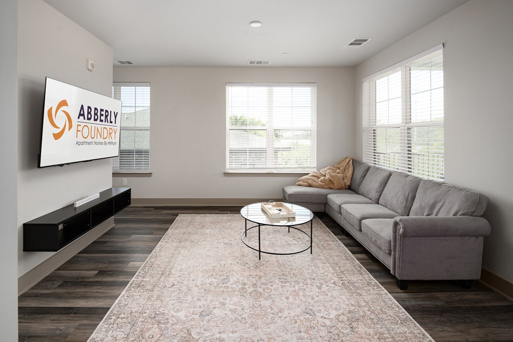 a living room with a couch and coffee table in front of a flat screen tv at Abberly Foundry Apartment Homes, Nashville, TN, 37203