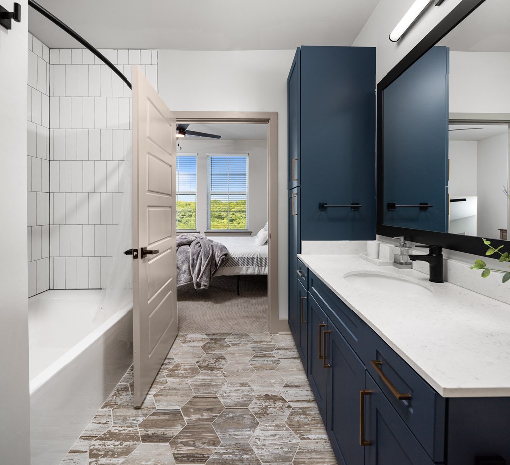 a bathroom with blue cabinets and a white bathtub at Abberly Foundry Apartment Homes, Nashville, Tennessee