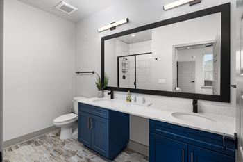 a bathroom with blue cabinets and a large mirror at Abberly Foundry Apartment Homes, Nashville