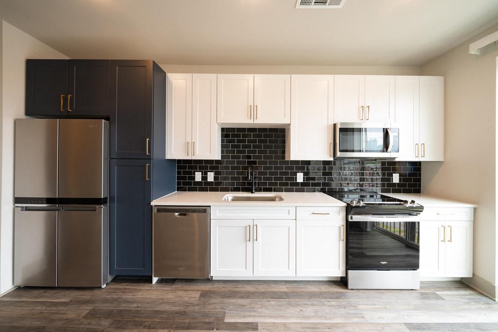 a kitchen with white cabinets and black and white appliances at Abberly Foundry Apartment Homes, Nashville, Tennessee