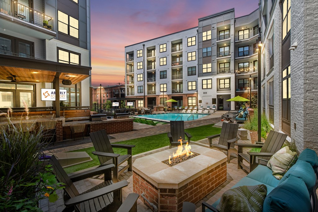 an outdoor lounge area with a fire pit and lounge chairs with a pool in the backgroundat Abberly Foundry Apartment Homes, Nashville, TN