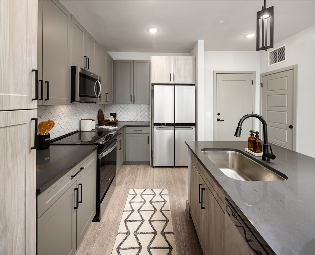 a kitchen with gray cabinets and a black and white rug  at Abberly Foundry Apartment Homes, Nashville, TN, 37203