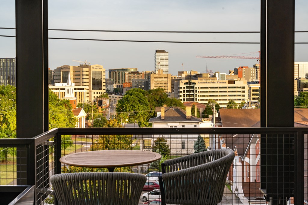 a balcony with two chairs and a table with a view of the city at Abberly Foundry Apartment Homes, Nashville