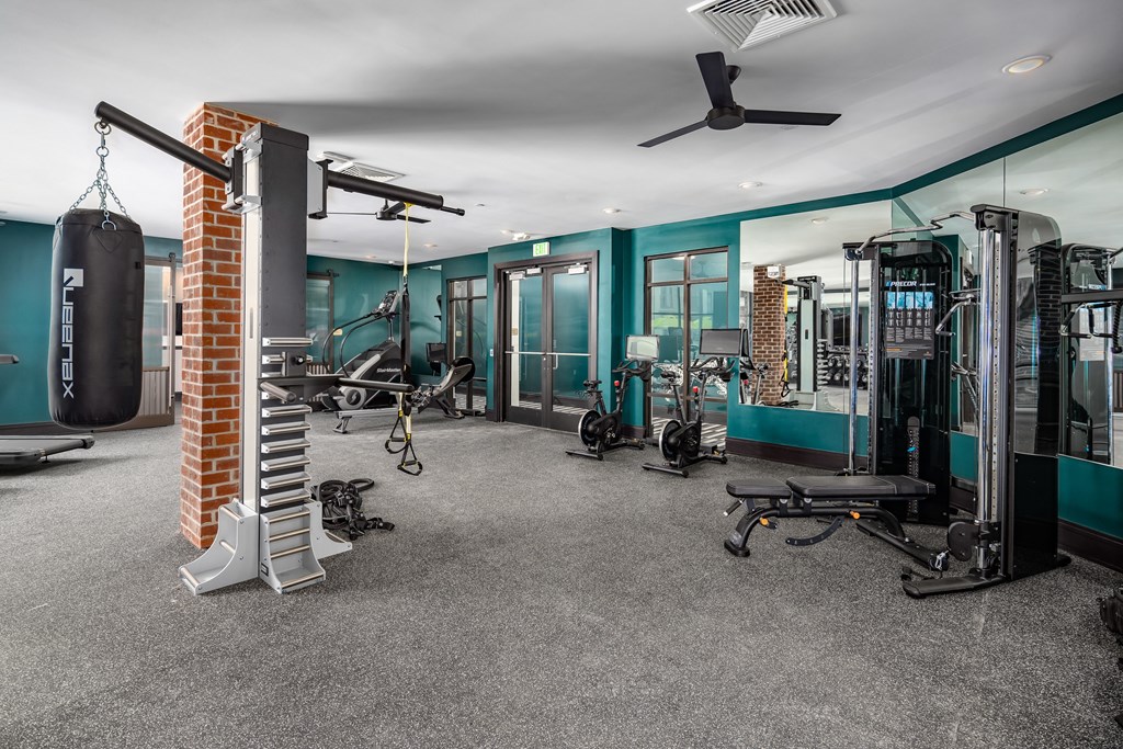 a gym with a lot of exercise equipment and a brick column in the middle of the room at Abberly Foundry Apartment Homes, Nashville