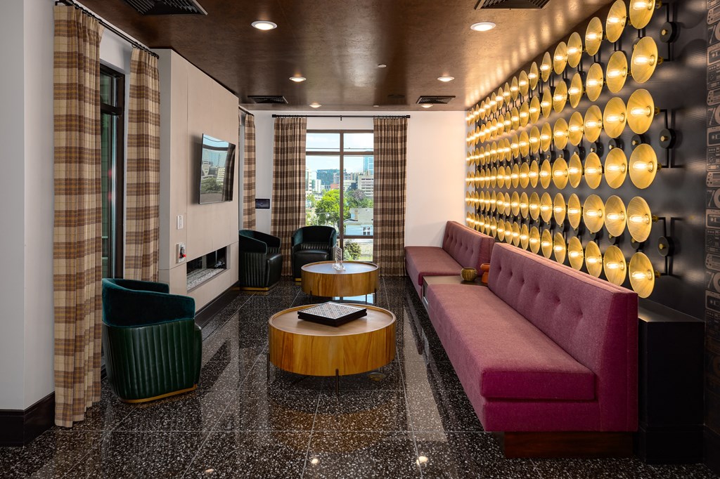 a seating area with a purple couch and a wooden coffee table in front of a wall with at Abberly Foundry Apartment Homes, Nashville, TN, 37206