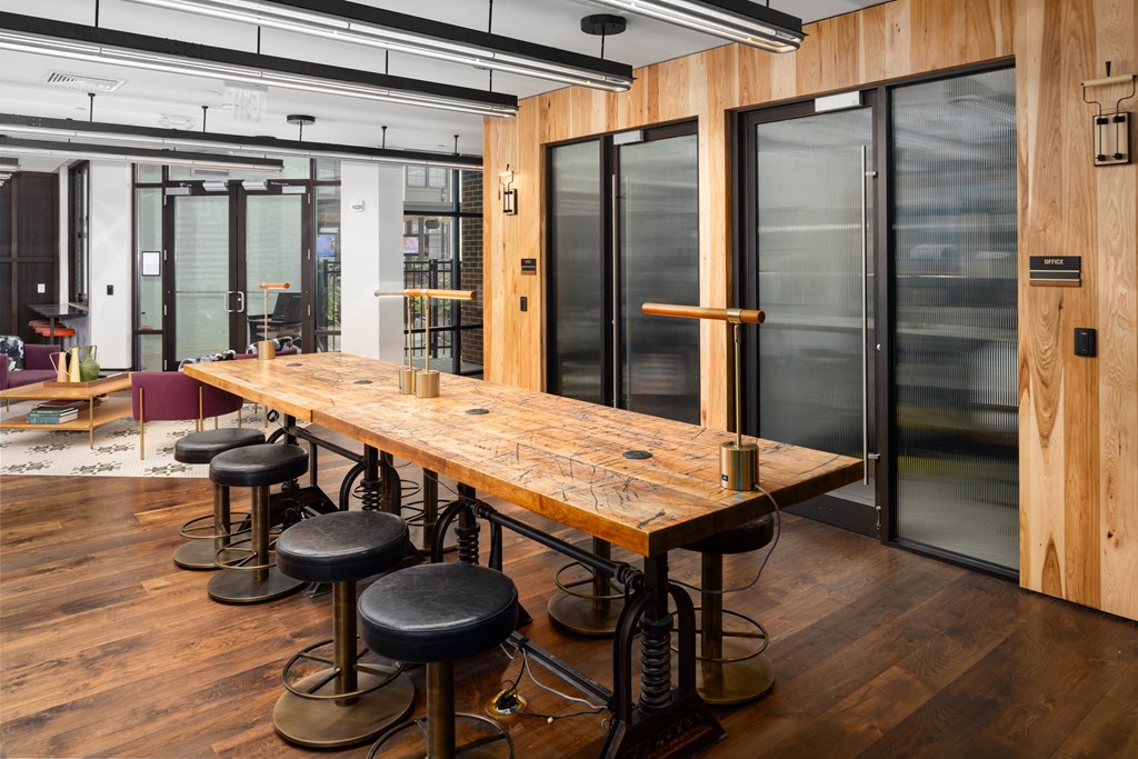 a long wooden table with black stools in a room with glass doors at Abberly Foundry Apartment Homes, Nashville, Tennessee