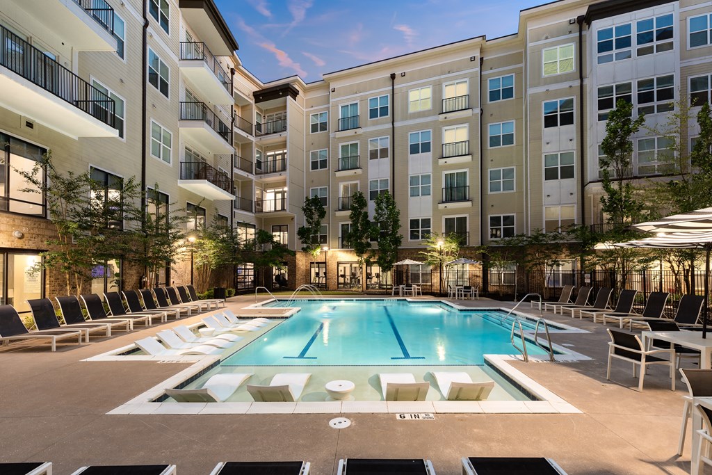 a pool with lounge chairs and umbrellas in front of an apartment building  at Abberly Onyx Apartment Homes, Decatur, 30033
