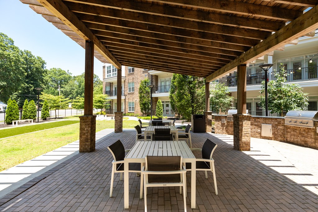 a patio with a wooden pergola and tables and chairs  at Abberly Onyx Apartment Homes, Georgia, 30033