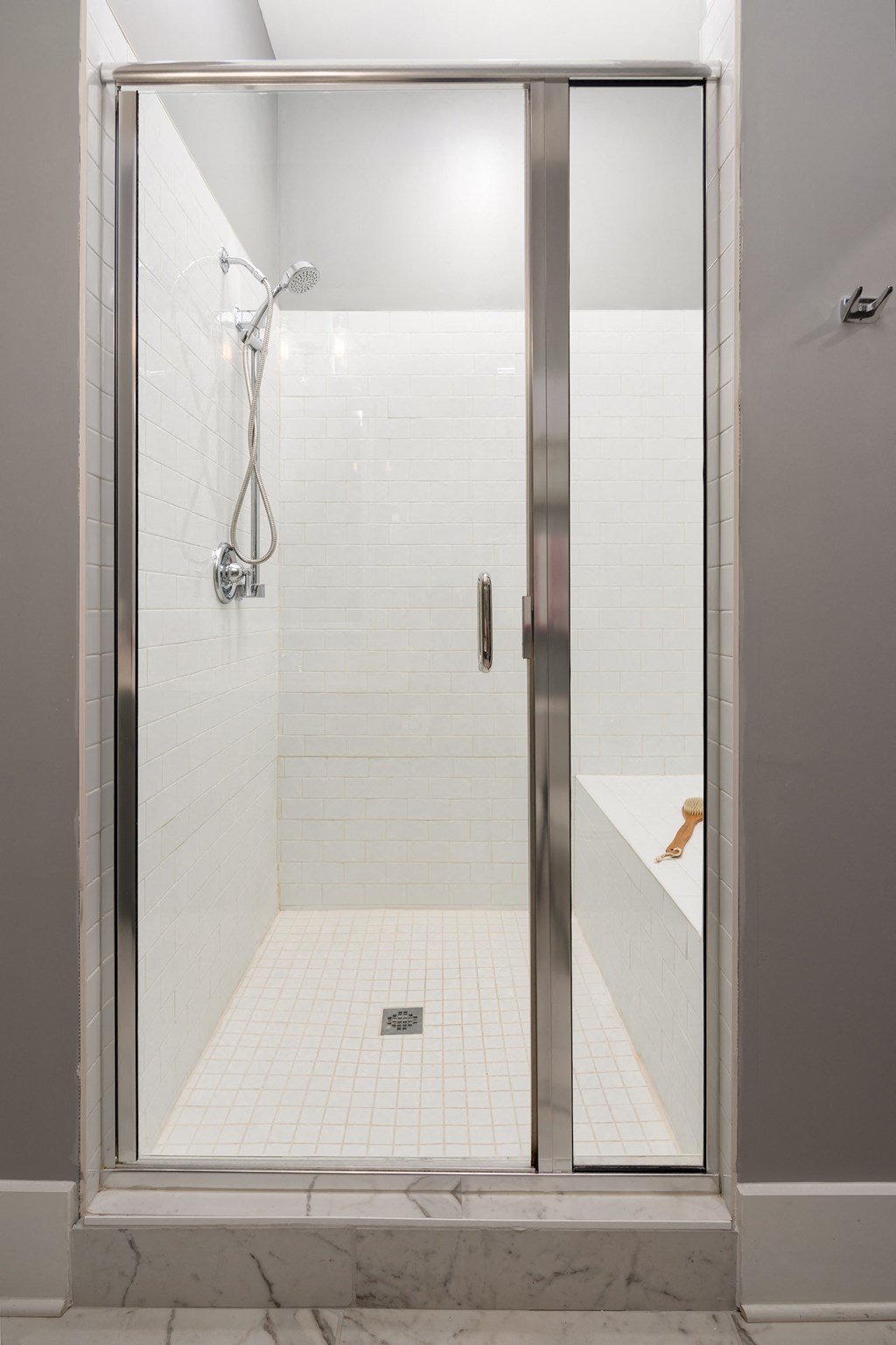 the shower in the master bathroom has a glass door and white tiles