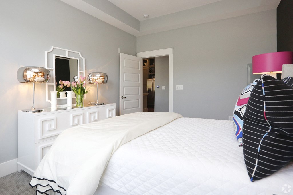 a bedroom with a large white bed and a white dresser with two lamps and