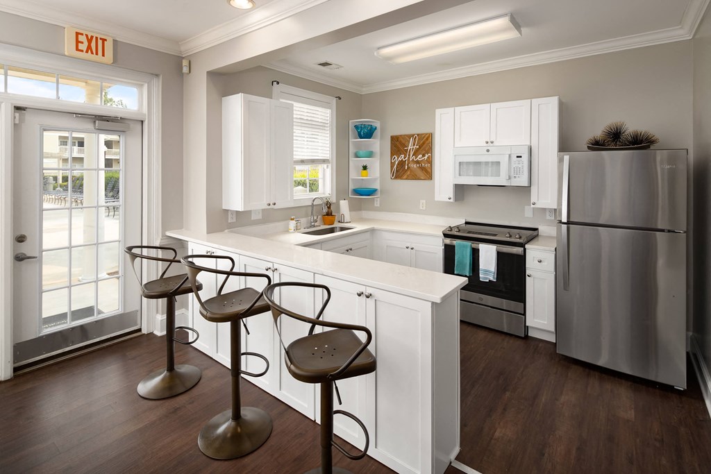 a kitchen with white cabinetry and a white counter top with three stools in front of  at Abberly Grove Apartment Homes, Raleigh, NC