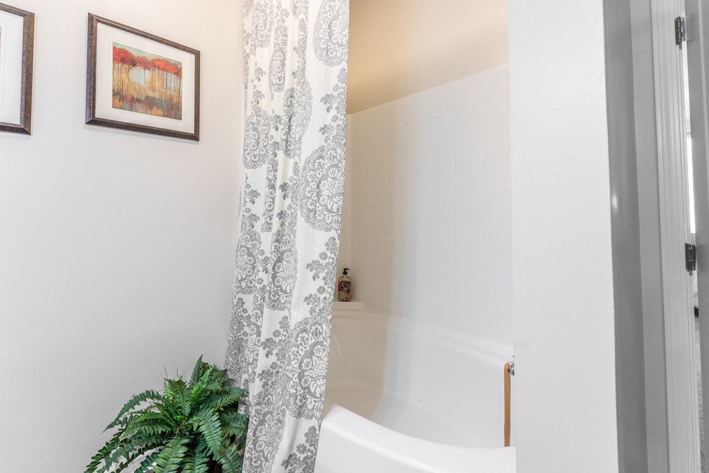 a bathroom with a bathtub and a plant in the corner at Abberly Crest Apartment Homes, Lexington Park, 20653