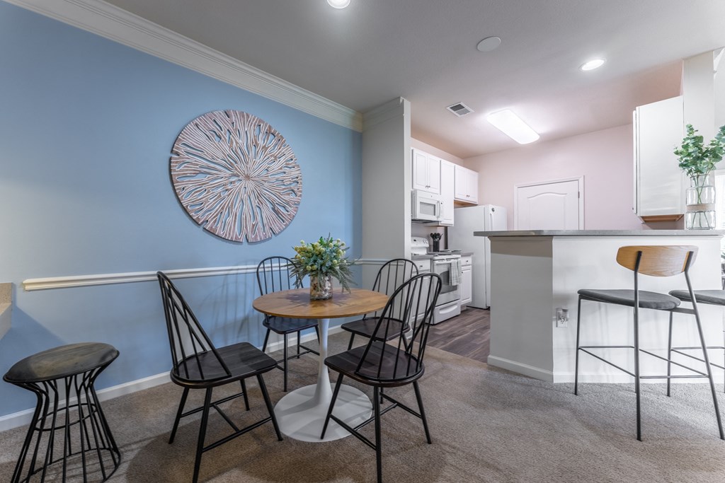 a dining area with a small table and chairs and a kitchen in the background at Abberly Crest Apartment Homes, Lexington Park, Maryland