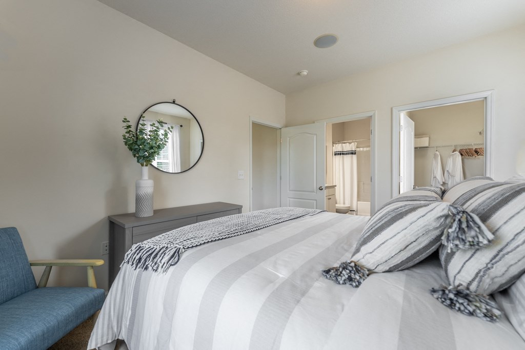 a bedroom with a large bed and a blue chair at Abberly Crest Apartment Homes, Lexington Park, MD
