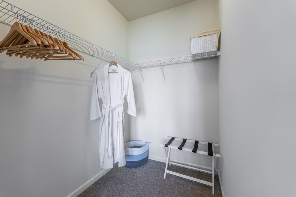 a dressing room with a white robe and wooden hangers at Abberly Crest Apartment Homes, Lexington Park, Maryland