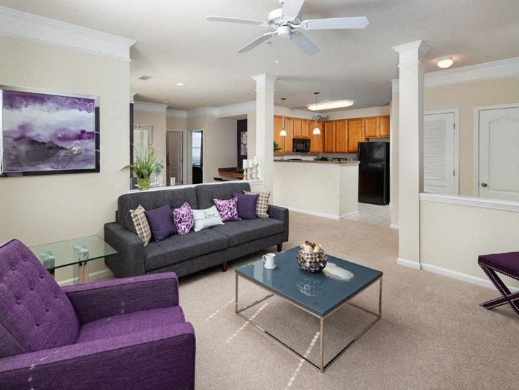 a living room with purple furniture and a kitchen in the background at Abberly Crest Apartment Homes, Maryland