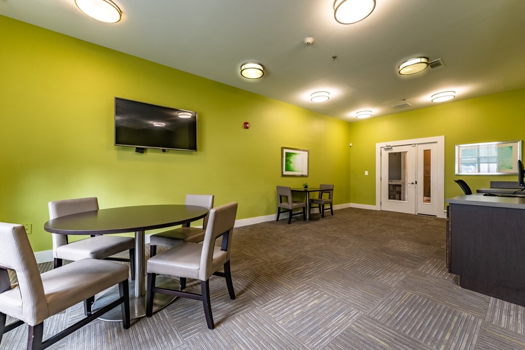a room with a table and chairs and a flat screen tv on the wall at Abberly Crest Apartment Homes, Lexington Park