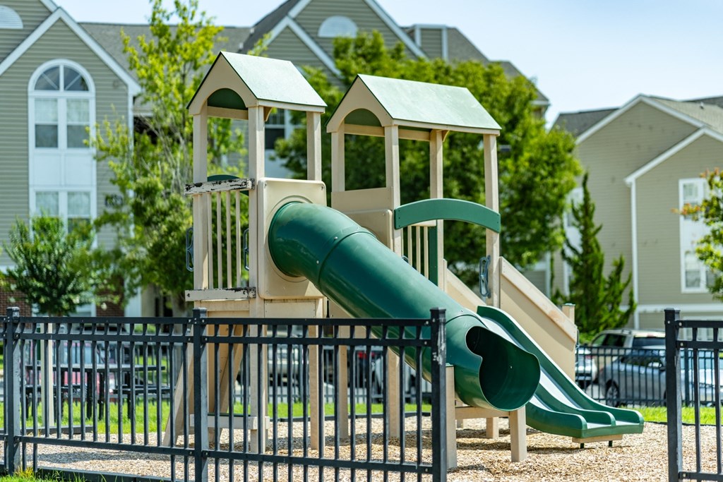 a playground with a slide in front of a row of houses at Abberly Crest Apartment Homes, Lexington Park, MD, 20653