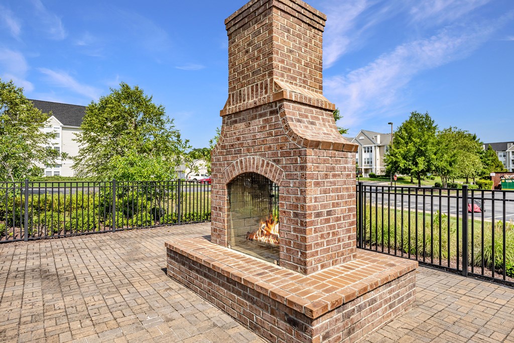 an outdoor brick fireplace with a stone mantel sits on a brick patio in front of a at Abberly Crest Apartment Homes, Maryland, 20653