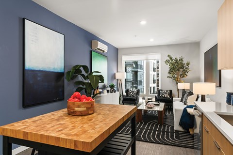 A modern kitchen with a wooden table and a bowl of fruit on it.