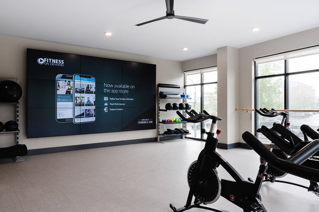 a gym with exercise equipment and a large screen on the wall