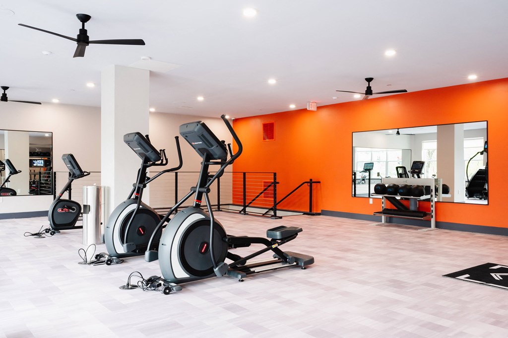 a gym with treadmills and other exercise equipment in a room with orange walls