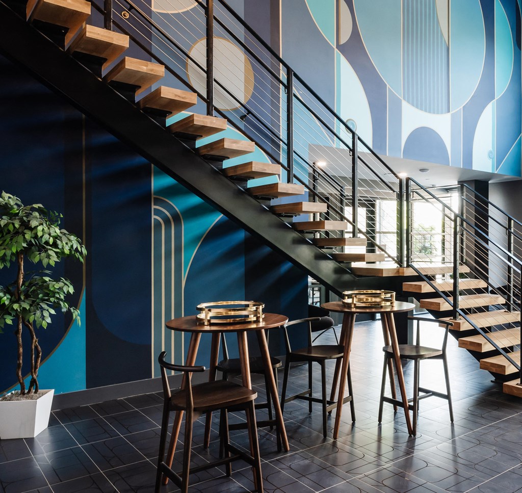 a dining room with tables and chairs under a staircase