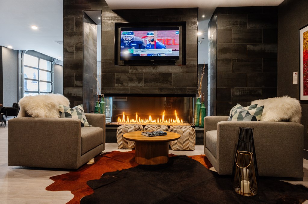 a living room with two chairs and a fireplace with a tv above it