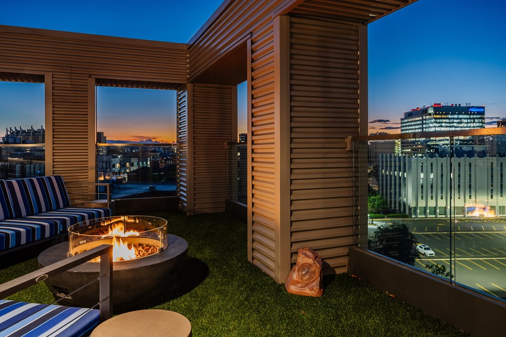 a balcony with a fire pit and a view of the city at night