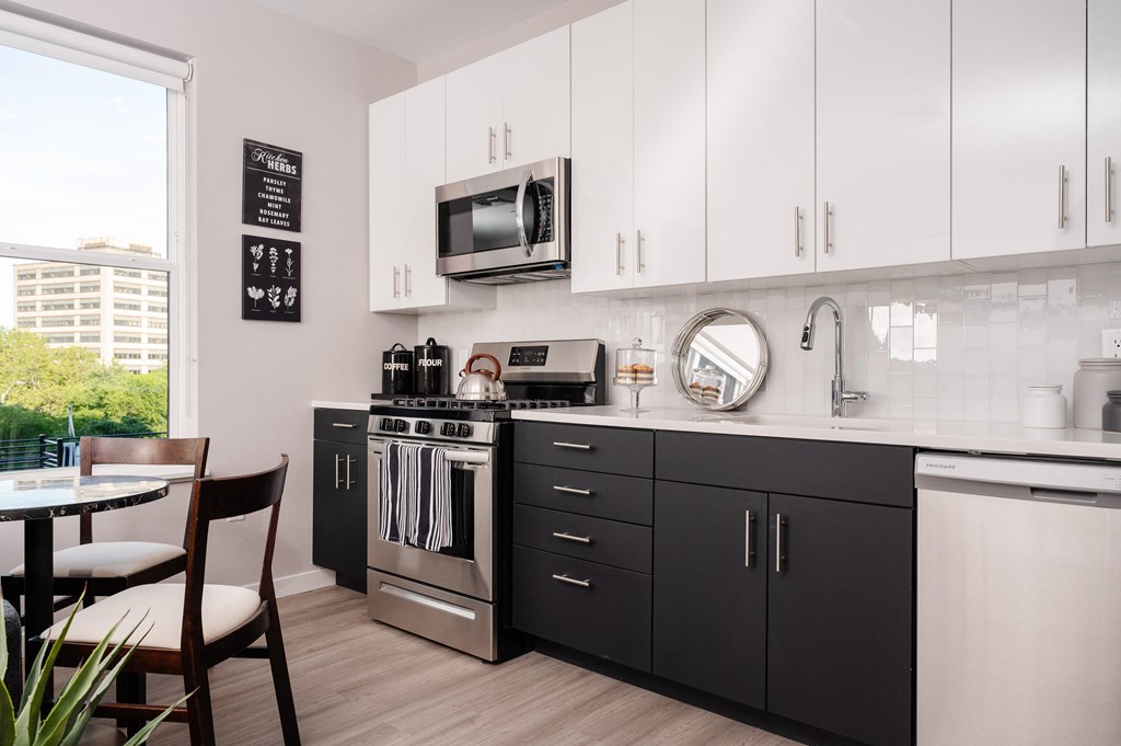 a kitchen with black and white cabinets and stainless steel appliances and a window