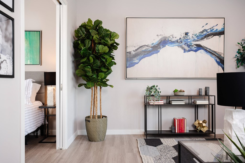 a living room with a large plant and a painting on the wall