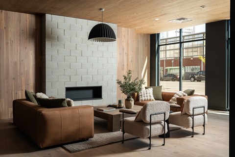 A living room with a brown leather couch, a white brick wall, and a fireplace.