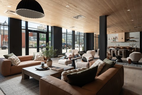 A modern living room with brown leather couches and a wooden ceiling.