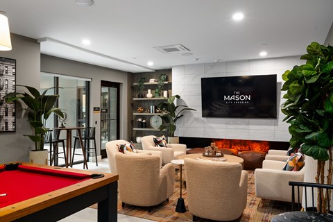 A pool table is in the middle of a living room with a couch and chairs around it.